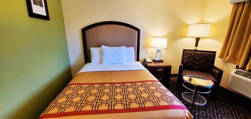 a hotel room with a bed and a chair at Travel Inn and Suites- Sikeston Miner I-55 exit-67 in Sikeston