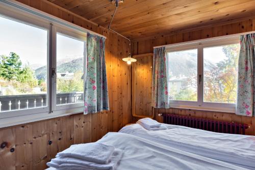 - une chambre avec deux fenêtres et un lit dans l'établissement Chalet Speciale - Celerina, à Celerina