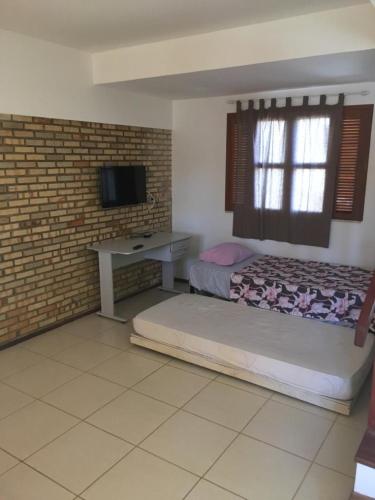 a bedroom with a bed and a desk and a television at Club house in Prainha