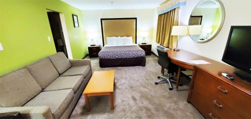 a hotel room with a bed and a couch and a desk at Travel Inn and Suites- Sikeston Miner I-55 exit-67 in Sikeston