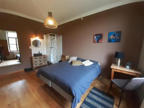 a bedroom with a blue bed and a chair at Le Thirifays in Chiny