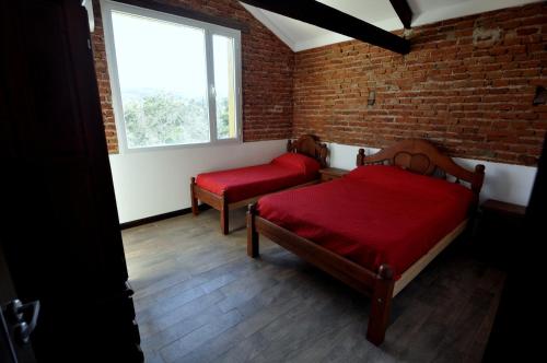 two beds in a room with a brick wall at Hotel y cabañas FATVIAL 4 de Abril in Tanti