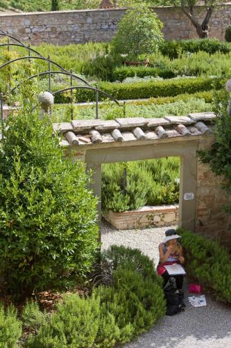 a man sitting on a bench under a bridge in a garden at Castello Di Meleto in Gaiole in Chianti