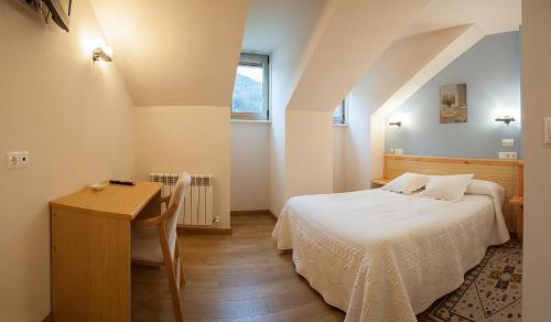 a small bedroom with a bed and a desk and a window at Hotel San Briz in A Pontenova