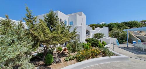 a large white building with trees and plants at Sarakiniko Rooms in Adamas
