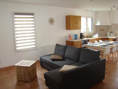 a living room with a blue couch and a kitchen at Maison confortable dans le Périgord pourpre in Lamonzie-Saint-Martin