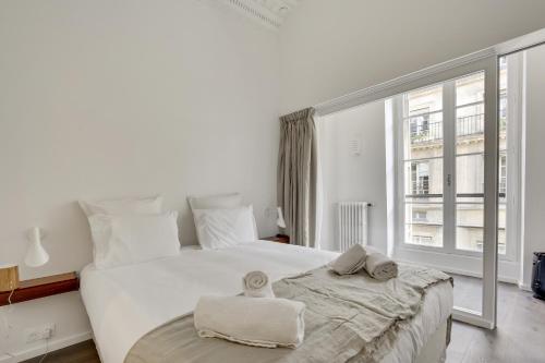 - une chambre blanche avec un grand lit et une grande fenêtre dans l'établissement Modern Apt 3BDR/3BATH - Louvre Museum/Tuileries, à Paris