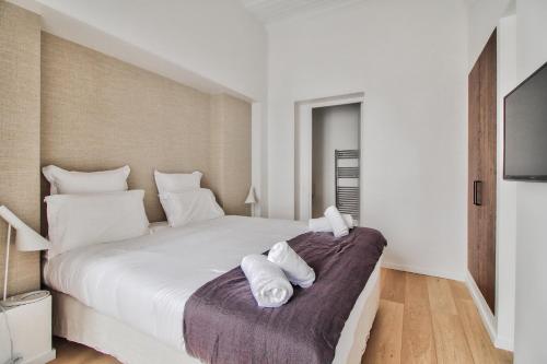 une chambre avec un grand lit blanc avec des serviettes dessus dans l'établissement Modern Apt 3BDR/3BTH - Louvre Museum/Tuileries, à Paris