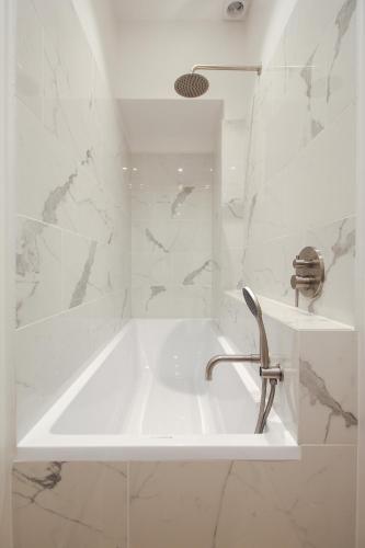 une salle de bain blanche avec un lavabo et une baignoire dans l'établissement Modern Apt 3BDR/3BTH - Louvre Museum/Tuileries, à Paris