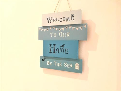 Ein Zeichen, das sagt, willkommen in unserem Haus am Meer in der Unterkunft Seaside Cottage with Parking in Worthing