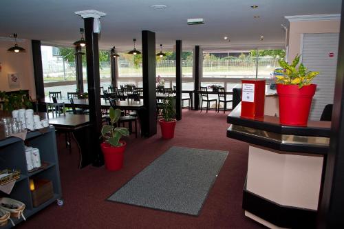 un restaurant avec des tables, des chaises et des plantes en pot dans l'établissement Quick Palace Poitiers, à Chasseneuil-du-Poitou