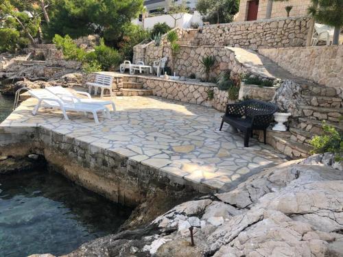 une terrasse en pierre avec des chaises et une piscine d'eau dans l'établissement Villa Vlajina, à Primošten