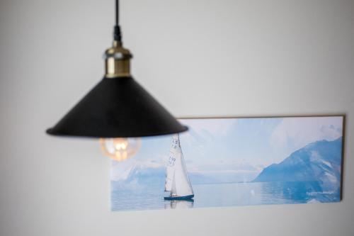 a black lamp with a sail boat in front of a picture at Hotel Olimpija plus in Herceg-Novi