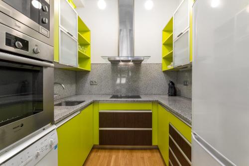 a yellow kitchen with white and gray cabinets at San Martin 2 - Local Rentss in San Sebastián