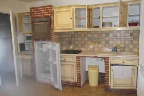 a kitchen with wooden cabinets and a brick wall at SCI AUBENIZEL 21 in Aubigny-aux-Kaisnes