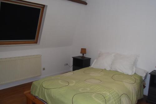 a bedroom with a green bed with a television on the wall at SCI AUBENIZEL 21 in Aubigny-aux-Kaisnes