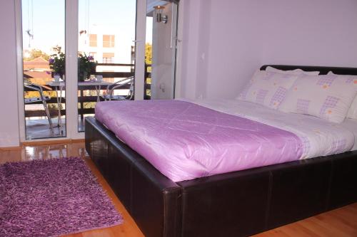 a bed in a room with a purple blanket at Comfort Deluxe Kosmos Apartments in Ohrid