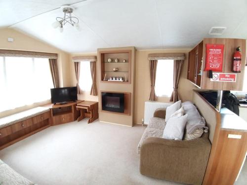 uma sala de estar com um sofá e uma televisão em Clwyd 6 em Borth