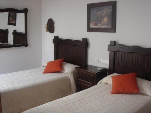 two beds with orange pillows in a bedroom at Casa Maika in Montoro