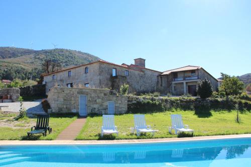 a house with two lawn chairs and a swimming pool at Casa Da Gaiteira in Vieira do Minho