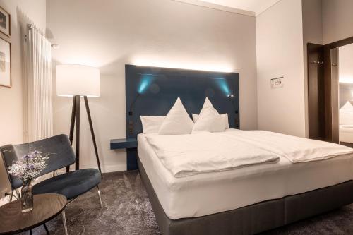 a bedroom with a large white bed and a chair at Villa Rein Boutiquehotel in Bad Reichenhall