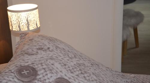 a bed with a comforter on it with a lamp at Lodge Hotel Les Rousses in Les Rousses
