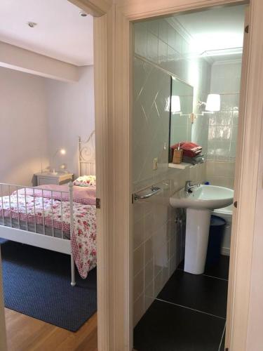 een badkamer met een wastafel en een bed met een spiegel bij bed and beach laredo in Laredo