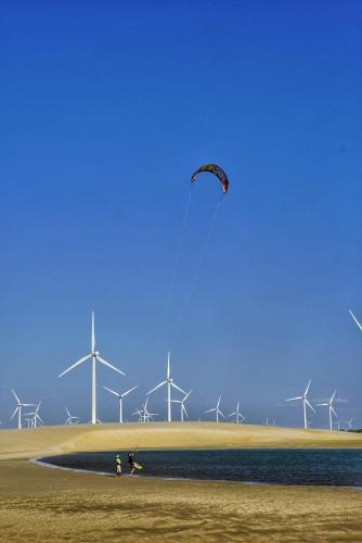 a person flying a kite in front of windmills at Pousada Peixe Galo in Galinhos