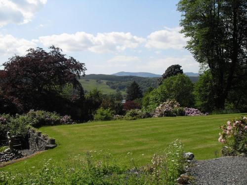 a garden with green grass and flowers and trees at Sawrey House in Near Sawrey