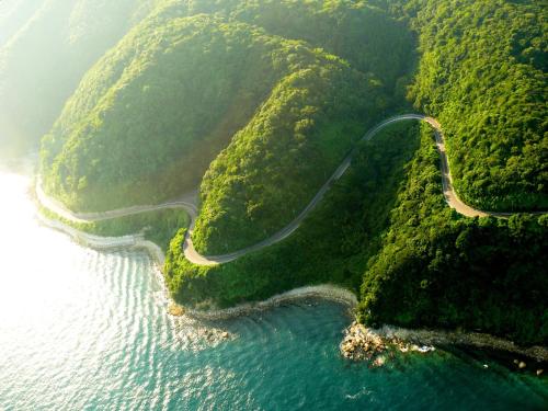 a road on the side of a mountain next to the water at Fukumakan in Matsue