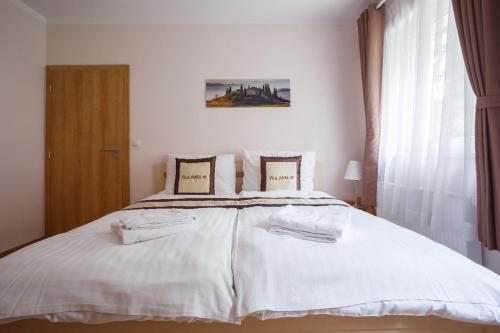 um quarto com uma cama branca com lençóis e almofadas brancos em Diana Apartments Karlovy Vary em Karlovy Vary