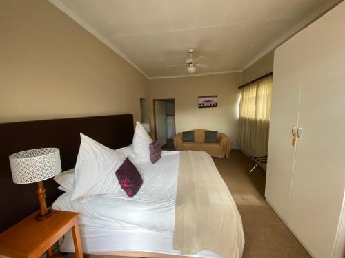 a bedroom with a bed with white sheets and pillows at Lanseria Country Estate in Lanseria