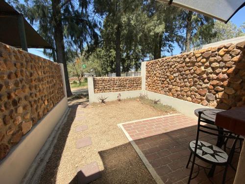 a patio with a stone wall and a table and chairs at Lanseria Country Estate in Lanseria