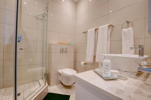 a white bathroom with a toilet and a shower at Bay Lodge on the Beach in Mossel Bay