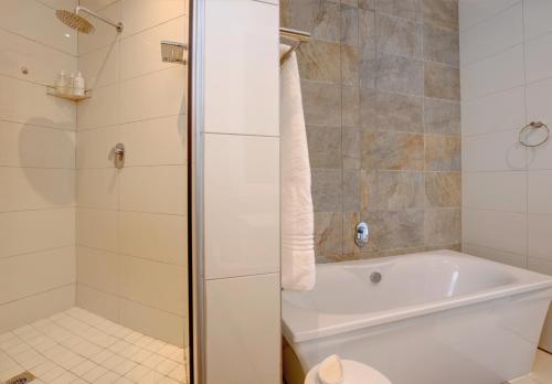 a bathroom with a white tub and a shower at Bay Lodge on the Beach in Mossel Bay
