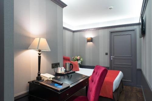 a hotel room with a desk and a bed and a bed and a room at Alexandra in Lyon