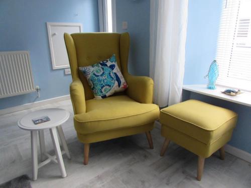 einen gelben Stuhl und einen Stuhl in einem Zimmer in der Unterkunft The Cuddy - Apartment with garden in Brixham