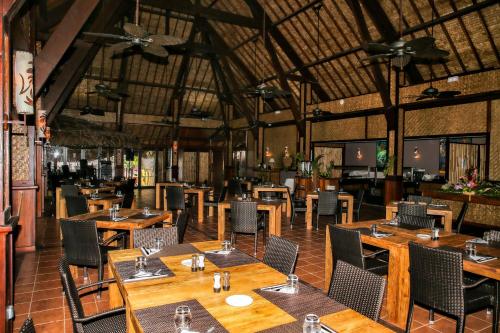 uma sala de jantar com mesas e cadeiras de madeira em ROYAL BORA BORA em Bora Bora