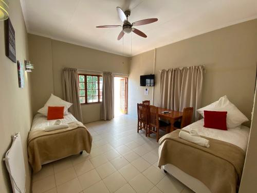 a bedroom with two beds and a table and a ceiling fan at Lanseria Country Estate in Lanseria