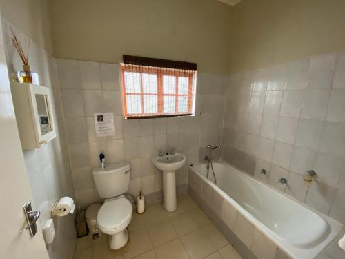 a bathroom with a toilet and a tub and a sink at Lanseria Country Estate in Lanseria
