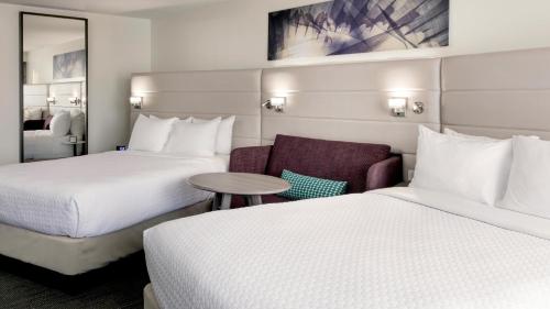 a hotel room with two beds and a chair and a table at Crowne Plaza Atlanta - Midtown by IHG in Atlanta