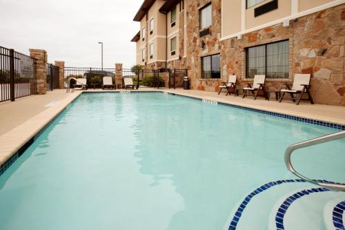 a large swimming pool with chairs and a building at Holiday Inn Express Marble Falls by IHG in Marble Falls