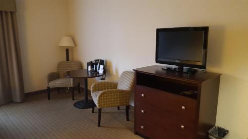a hotel room with a television on a dresser with a table at Holiday Inn Express Hotel & Suites Antigo, an IHG Hotel in Antigo