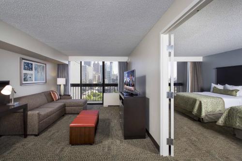 Staybridge Suites Atlanta - Midtown, an IHG Hotel في أتلانتا: غرفه فندقيه بسرير واريكه