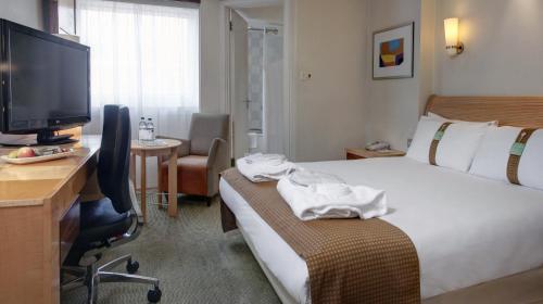 a hotel room with a bed and a desk and a television at Holiday Inn Basingstoke by IHG in Basingstoke