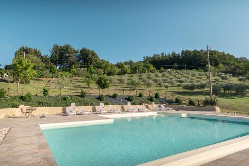 a swimming pool with chairs and a hill in the background at Agriturismo Dolce Sentire in Assisi