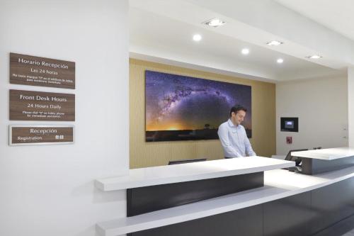 a man standing in a room with a large painting on the wall at Candlewood Suites - Celaya by IHG in Celaya