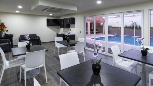 a dining room with tables and chairs and a swimming pool at Candlewood Suites - Celaya, an IHG Hotel in Celaya