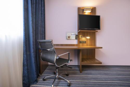 a room with a desk with a chair and a television at Holiday Inn Express Neunkirchen by IHG in Neunkirchen