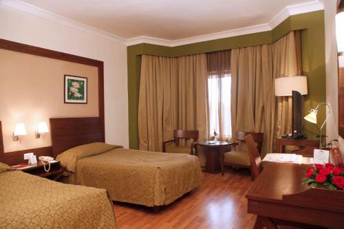 a hotel room with two beds and a desk at The Retreat Hotel & Convention Centre in Mumbai